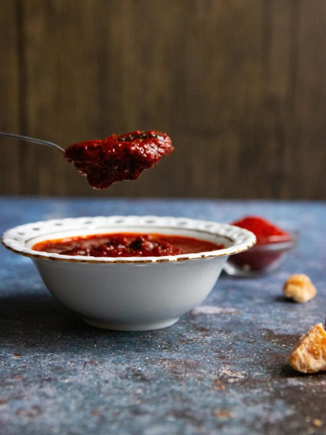 A spoon dipping into the chili for a taste test.