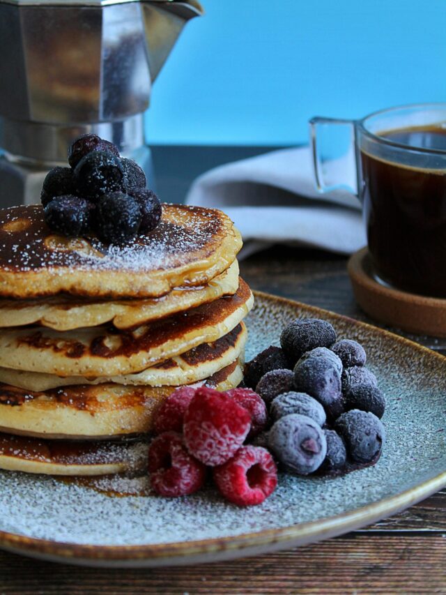 A cozy breakfast table setup with pancakes, juice, and coffee